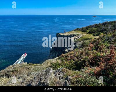 Der Mensch steht allein am Rande einer steilen Klippe und überblickt den Atlantischen Ozean. Stockfoto