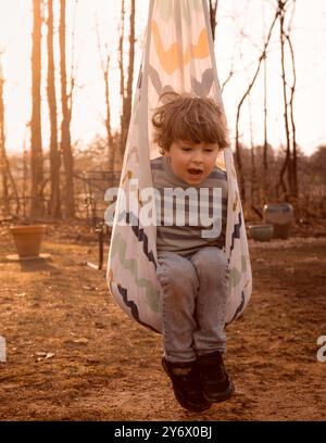 Kind in Eierschaukel auf dem Spielplatz im Wald im Herbst Stockfoto