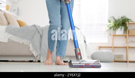 Frau, die den Boden mit schnurlosem Staubsauger in Innenräumen reinigt, Nahaufnahme Stockfoto