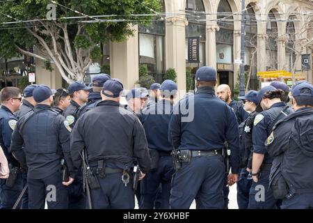 San Francisco, CA - 03. März 2024: SFPD-Offiziere drängen sich, um Sicherheit für einen Marsch gegen Antisemitismus auf der Market Street zur Civic CE zu bieten Stockfoto