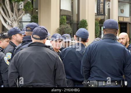 San Francisco, CA - 03. März 2024: SFPD-Offiziere drängen sich, um Sicherheit für einen Marsch gegen Antisemitismus auf der Market Street zur Civic CE zu bieten Stockfoto