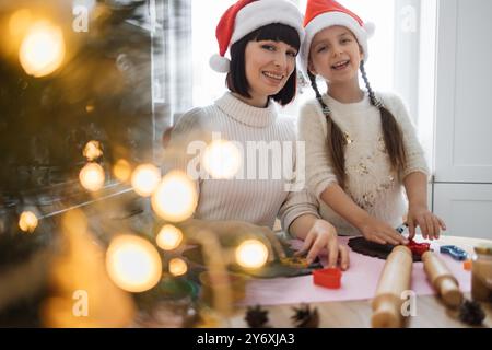 Mutter und Tochter backen Weihnachtskekse in Weihnachtsmützen Stockfoto