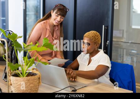 Zusammenarbeit bei der Arbeit, zwei Frauen verwenden Laptop und diskutieren Dokumente im Büro Stockfoto