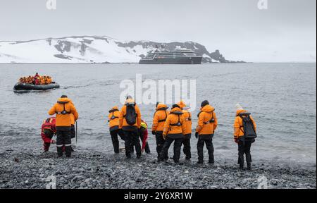 Half Moon Island, Antarktis - 9. Januar 2024: Seabourn-Kreuzfahrtpassagiere putzen ihre Stiefel an der Küste und kehren mit einem Sternzeichen zum Schiff zurück. Stockfoto