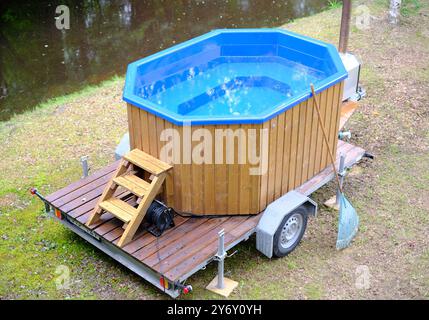 Ein kleiner Pool steht auf einem Wohnwagen. Der Pool ist blau und aus Holz. Es gibt eine Leiter, um in die und aus der Kacke zu kommen Stockfoto