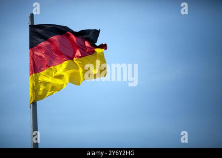 Die deutsche Flagge winkt sanft im Wind und symbolisiert an einem sonnigen Tag den Nationalstolz in Berlin. Stockfoto