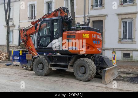 Nancy, Frankreich - Blick auf einen orangefarbenen Radbagger Hitachi ZX145 W-6 für Erdarbeiten auf einer Baustelle für Arbeiten am Trinkwassernetz. Stockfoto