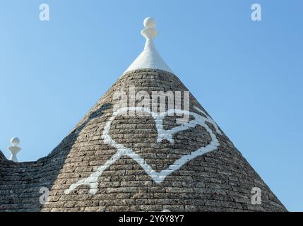 Weißes Herz auf einem traditionellen Trulli-Dach in alberobello, einer kleinen Stadt in apulien, italien, die für ihr weißgetünchtes konisches Dach berühmt ist Stockfoto