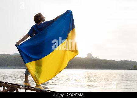 Eine Frau hält eine große ukrainische gelb-blaue Flagge hinter ihrem Rücken Stockfoto