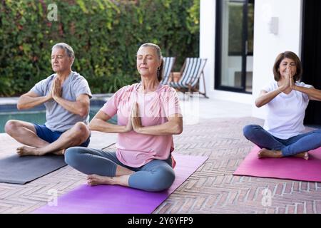 Yoga praktizieren, verschiedene ältere Freunde meditieren auf Matten im Freien, konzentrieren sich auf Achtsamkeit, in hom Stockfoto