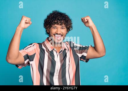 Foto von nettem jungen Mann, der Fäuste trägt Hemd isoliert auf blaublauem Hintergrund Stockfoto
