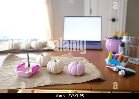 Malerei White Mini Pumpkins Pink mit Laptop im Hintergrund Stockfoto