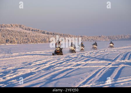 Schneemobile, die im Winter über den gefrorenen Inari-See fahren, Nordfinnland (Lappland, Finnland) ESP: Motos de nieve pasando por encima del lago hel Stockfoto