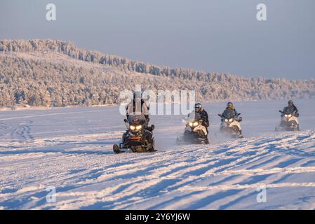 Schneemobile, die im Winter über den gefrorenen Inari-See fahren, Nordfinnland (Lappland, Finnland) ESP: Motos de nieve pasando por encima del lago hel Stockfoto