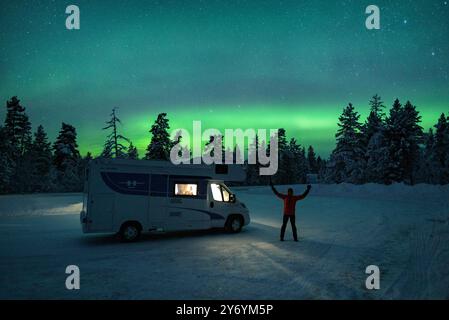 Nordlichter über einem Wohnmobil und einem verschneiten Wald bei Nacht (Lappland, Finnland) ESP: Aurora boreal Erfahren Sie mehr über autocaravana y un bosque nevado Stockfoto