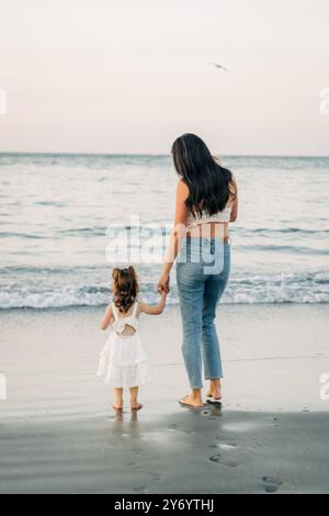 Mutter und Tochter halten Hände, stehen am Ufer Stockfoto