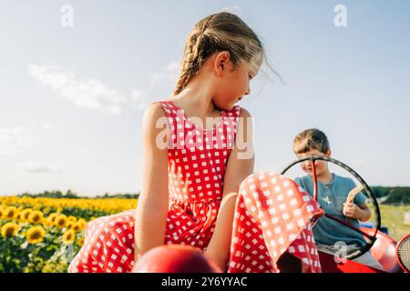 Ein Mädchen in einem roten karierten Kleid, das auf einem Traktor sitzt Stockfoto