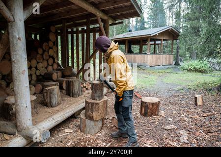 Ein Mann, der mit einer Axt Brennholz hackt, um im Wald Feuer zu machen Stockfoto