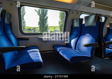 Leersitze in einem öffentlichen Personenzug in der Schweiz, Europa. Weitwinkel, natürliches Fensterlicht, keine Personen. Stockfoto