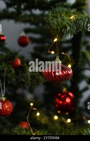 Rote Weihnachtsdekorationen auf einem weihnachtsbaum, funkelnde rote weihnachtsbaumkugeln auf künstlichem Baum, Nahaufnahme von roten weihnachtsbaumschmuck Stockfoto