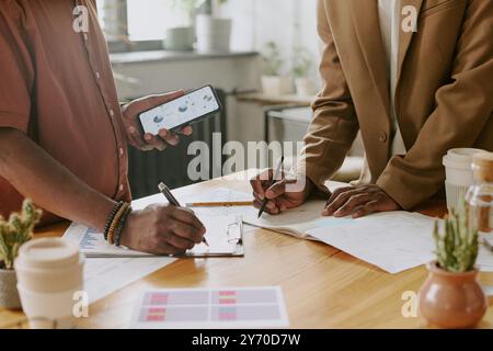 Nicht erkennbare Kollegen, die Diagramme und Grafiken auf Papier erstellen Stockfoto