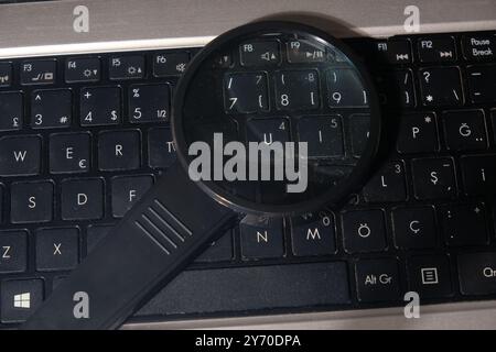 Modernes Vergrößerungsglas auf einer schwarzen Laptop-Tastatur in einer von der Technik inspirierten Nahaufnahme Stockfoto