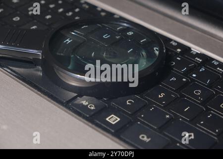 Modernes Vergrößerungsglas auf einer schwarzen Laptop-Tastatur in einer von der Technik inspirierten Nahaufnahme Stockfoto