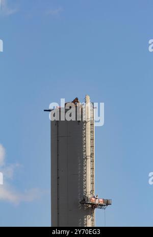 Bochum, Rückbau des Opelwerks. 25.06.2015, EU, DEU, Deutschland, Nordrhein-Wstfalen, Bochum: Strukturwandel im Ruhrgebiet. Abrissarbeiten am ehemaligen Opelwerk. Ein ferngesteuerter Bagger reist den fast 100 Meter hoher Schornstein der Opel-Lackiererei im Werk 1 an der Wittener Straße ab. EU, DEU, Deutschland, Nordrhein-Westfalen, Bochum: Strukturwandel im Ruhrgebiet. Abbrucharbeiten im ehemaligen Opel-Werk. Ein ferngesteuerter Bagger zerstört den fast 100 Meter hohen Schornstein der Opel Lackiererei im Werk 1 an der Wittener Straße. Stockfoto