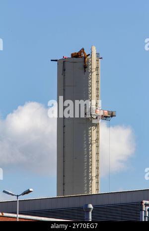 Bochum, Rückbau des Opelwerks. 25.06.2015, EU, DEU, Deutschland, Nordrhein-Wstfalen, Bochum: Strukturwandel im Ruhrgebiet. Abrissarbeiten am ehemaligen Opelwerk. Ein ferngesteuerter Bagger reist den fast 100 Meter hoher Schornstein der Opel-Lackiererei im Werk 1 an der Wittener Straße ab. EU, DEU, Deutschland, Nordrhein-Westfalen, Bochum: Strukturwandel im Ruhrgebiet. Abbrucharbeiten im ehemaligen Opel-Werk. Ein ferngesteuerter Bagger zerstört den fast 100 Meter hohen Schornstein der Opel Lackiererei im Werk 1 an der Wittener Straße. Stockfoto