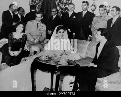 Prinzessin Shahnaz Pahlevi , 17-jährige Tochter des iranischen Schah Reza Pahlevi und seiner ersten Frau , saß mit ihrem Ehemann Ardeshi Zahedi , dem Sohn von General Fazollah Zahedi , einem ehemaligen iranischen Premierminister kurz nach der Hochzeitszeremonie . Auf der linken Seite sitzt Königin Soraya von Persien , auf dem Arm sitzt ihr Mann der Schah von Persien und dahinter sind Onkel . 12. Oktober 1957 Stockfoto