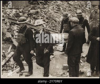 WACHMÄNNER HELFEN BEI DER RETTUNGSARBEIT IM BOMBARDIERTEN RASTZENTRUM. Wachmänner helfen Air RAID Vorkehrungen Rettungstruppen, um Menschen zu befreien, die von Trümmern begraben wurden, als eine öffentliche Halle in London von deutschen Nachträubern bombardiert wurde. Die Halle wurde als Raststätte für Menschen genutzt, die aus ihren Häusern bombardiert worden waren. FOTO ZEIGT: Rettungskräfte dehnen einen der Opfer aus dem Wrack aus. 18. Oktober 1940 Stockfoto