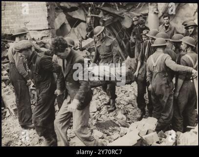 WACHMÄNNER HELFEN BEI DER RETTUNGSARBEIT IM BOMBARDIERTEN RASTZENTRUM. Wachmänner helfen Air RAID Vorkehrungen Rettungstruppen, um Menschen zu befreien, die von Trümmern begraben wurden, als eine öffentliche Halle in London von deutschen Nachträubern bombardiert wurde. Die Halle wurde als Raststätte für Menschen genutzt, die aus ihren Häusern bombardiert worden waren. FOTO ZEIGT: Rettungskräfte dehnen einen der Opfer aus dem Wrack aus. 17. Oktober 1940 Stockfoto