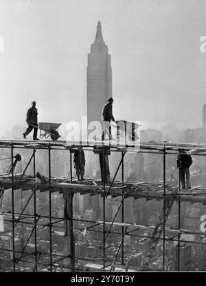 New York. Eine neue Sicht auf die Fortschritte beim Bau des Weltquartiers der Vereinten Nationen in New York City. Arbeiter arbeiten an diesem Denkmal des Friedens und fahren ihre Schubkarren aus Zement im neununddreißigsten Stock des Secretarist Building, im Schatten von New Yorks höchstem Wolkenkratzer. Das Empire State Building. 6. Dezember 1949 Stockfoto