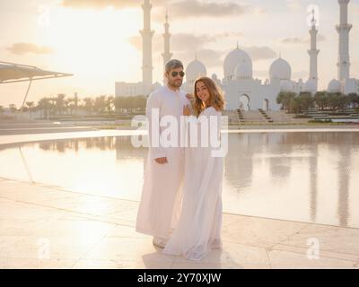 Reisen Sie in die Vereinigten Arabischen Emirate, Abu Dhabi. Arabisches Paar besucht den Park in der Nähe der Großen Moschee in Abu Dhabi in traditioneller Kleidung. Stockfoto