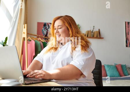 Die Frau in Übergröße genießt ihre Zeit beim Tippen auf dem Laptop, umgeben von einer fröhlichen Umgebung. Stockfoto