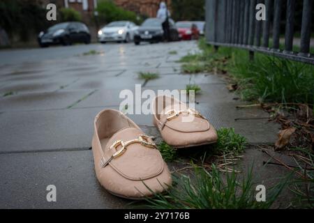 Ein Paar Damen-Slip-On-Schuhe wird am 27. September 2024 in London, England, unter einigen Parkgeländern gesehen, die vielleicht von jemandem zurückgelassen wurden, der sein Schuhwerk gewechselt hat. Stockfoto