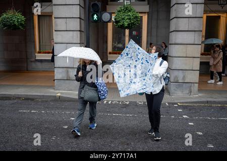 Zwei Frauen trotzen Wind und Regen und überqueren Piccadilly im West End am 26. September 2024 in London. Stockfoto