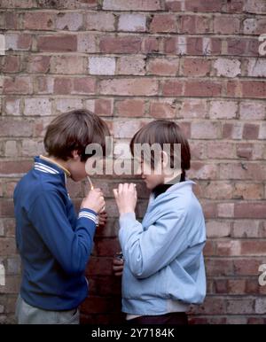 Zwei kleine Jungs rauchen hinter dem Fahrradschuppen 1970 Stockfoto