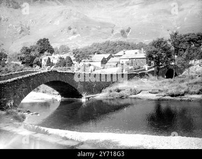 An der Doppelbrücke. Diese Doppelbrücke im malerischen Dorf grange im schönen Borrowdale Valley, Cumberland, ist bekannt für Urlauber im Lake District, die uns als Aussichtspunkt dienen, von dem aus man die vielen Forellen im Fluss beobachten kann. (Die nächstgelegene Bank ist das Eigentum des National Trust). Die Brücke befindet sich an einem Punkt, an dem sich der Fluss Derwent teilt, während er vom Talkopf zum Lake Derwentwater bei Keswick fließt. Sie führt die Straße zur Westseite von Derwentwater , von der aus man einen weiten Blick auf die Berge hat . 11. Juli 1957 Stockfoto