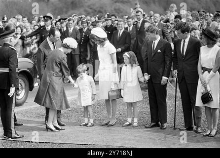 Jacqueline Kennedy begrüßt Königin Elizabeth II bei der Ankunft in Runnymede, Surrey. Mit Frau Kennedy sind ihre beiden Kinder Caroline (7) und John (4). Die Königin enthüllt das Denkmal in Runnymede für Mrs. Kennedys Ehemann , den verstorbenen US-Präsidenten John F. Kennedy . Auch der Bruder des verstorbenen Präsidenten , die Senatoren Edward und Robert Kennedy , werden anwesend sein . 14. Mai 1965 Lord Harlech auf der linken Seite Stockfoto