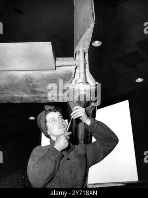 Ein Lächeln vom Wren Air Mechaniker Doreen Briggs aus Manchester, der den Heckstoßfänger eines Vampirflugzeugs an der Royal Naval Air Station in Lee-on-Solent, Hampshire, erlebte. Doreen , 16 Jahre alt , hat bereits einen einjährigen Dienst absolviert und unterstützt zusammen mit anderen Mitgliedern des Royal Naval Service der Frauen den Service von Rahmen, Motoren und Ausrüstung von Marineflugzeugen . 7. Februar 1952 Stockfoto