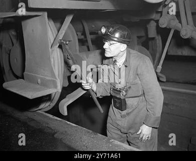 BERGBAULAMPEN LEUCHTEN DIE EISENBAHNEN - - - - British Railways haben eine Idee ihrer "Partner bei der Verstaatlichung " kopiert , die Einführung von Bergbaulampen für Arbeiter in Gruben unter Lokomotiven und an anderen Stellen , an denen solche Lampen nützlich sein könnten . - - - - DAS BILD ZEIGT :- LEICHTES KLOPFEN - - Ein Radklopfer mit einer der speziell konstruierten Kappen und einer Lampe , die mit kleinen Batterien am Gürtel betrieben wird . Er ist Herr . Richard Osborne in den Motorschuppen von Kentish Town ( London ) . - - 8. Februar 1949 Stockfoto