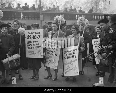 CHARS ON THE MARCH - MIT WISCHERN UND BÜRSTEN veranstalteten die Reinigerinnen von Regierungsbüros in London einen protestmarsch mit der Idee , die Aufmerksamkeit auf ihre Lohnerhöhungen zu lenken . Ihre Bemühungen richten sich an Sir Stafford Cripps . Sie fordern eine Erhöhung um 3 / 4 d pro Stunde . Unter der Leitung einer Pfeifenband marschierten die Putzfrauen mit Wischern und Bürsten durch die Londoner Straßen . Das Treffen wird eine Deputation wählen, die Sir Stafford Gripps trifft und die Lobby M. P's im Unterhaus. DAS BILD ZEIGT :- mit Mopps und Plakaten machen sich die Putzfrauen bereit, ihren protestmarsch zu beginnen Stockfoto