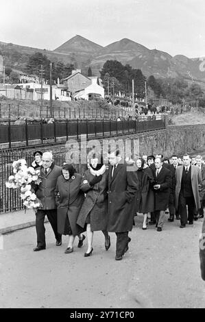 Aberfan-Katastrophe 1966 Trauernde begeben sich auf den Friedhof, wo heute 80 Kinder und ein Erwachsener - Opfer der Kohleschlammlawine vom 21. Oktober 1966 - beerdigt wurden. In der oberen rechten Ecke ist die Kohlespitze zu sehen, die in dieses Bergbaudorf rutschte. Bei der heutigen Massenbeerdigung waren 10.000 Personen anwesend, aber es waren Verwandte, Dorfbewohner und Bergleute aus den 15 Zechen in der Umgebung. 27. Oktober 1966 Stockfoto