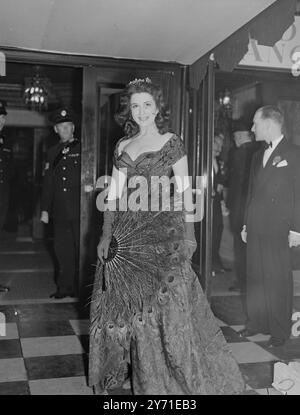 PFAU UND SPITZE - ADENA ROMNEY KOMMT ZUR ROYAL SHOW Filmstar ADENA ROMNEY macht ein glamouröses Bild in ihrem Spitzenkleid und trägt einen Pfauenfedern-Fan, als sie durch die Menschenmassen im Empire Theatre , Leicester Square , London zur Royal Command Film Show kommt , an der die Königin , Prinzessin Margaret und der Herzog von Edinburgh teilnahmen . Der König konnte wegen Krankheit nicht teilnehmen , fast 50 britische und amerikanische Stars gaben nach dem Film Scott of Antarctic eine Bühnenshow . 29. November 1948 Stockfoto