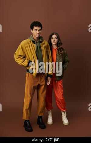 Ein stilvolles Paar präsentiert trendige Herbstoutfits mit kräftigen Farben und Texturen. Stockfoto