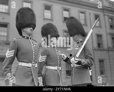 GOLDSTREAM WACHEN WERA NEUE KRIEGSMEDAILLEN. Als die Männer der Coldstream Guards zur Truppe der Farben zogen, wurden sie zum ersten Mal seit juni 1939 in ihre volle zeremonielle Kleidung gekleidet. In ihrem traditionellen, blauen und roten Kleid , mit Bärenfellmützen und mit den kürzlich erschienenen neuen Kriegsmappen , machten die Guraden einen spektakulären Anblick auf der Parade . DAS BILD ZEIGT: "Medaillen stimmen alle! Sgt R WHITFIELD (schottland) überprüft die neuen Kriegsmedaillen seines Kollegen sgt bei der Parade in Wellington Barracks . Juni 1948 Stockfoto