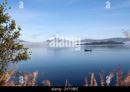 Boot auf Loch Lomond, Schottland mit frühmorgendlichem Licht von Inchmurrin mit Ben Lomond im Hintergrund. Stockfoto