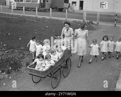 Kleine Tote suchen die Sonne. Unter den Menschenmassen, die heute Londons glorreichen Zauber des Sonnenscheins genossen, waren diese Kinder aus dem Waterloo Day Kindergarten, die während ihrer Verfassung entlang der Waterloo Road fotografiert wurden. Die Kinder im gestreckten Kinderwagen scheinen das Abenteuer genauso lustig zu machen wie ihre etwas älteren Kameraden zu Fuß. Die Krankenschwestern Betty Jones (links) und Nancy Tabor sind die sehr fähigen Escorts. 31. August 1948 Stockfoto