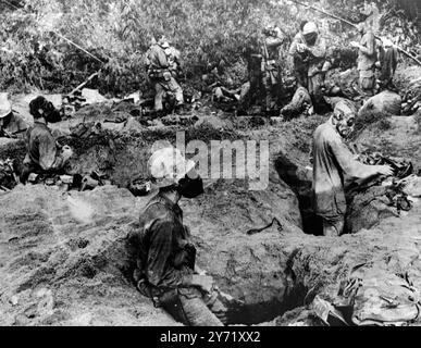 Lullt vor dem Sturm. An Hoa, Südvietnam: Mitglieder des Zweiten Bataillons der United States Marines 5th Marines, einige tragen Gasmasken, entspannen sich in und um die Fuchslöcher während einer Lulle während der Operation Essex in der Nähe. 17. November 1967 Stockfoto